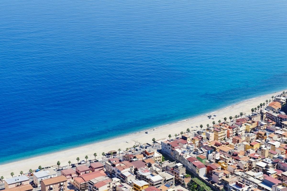 Vista panoramica di Diamante con famiglie in spiaggia e murales sullo sfondo