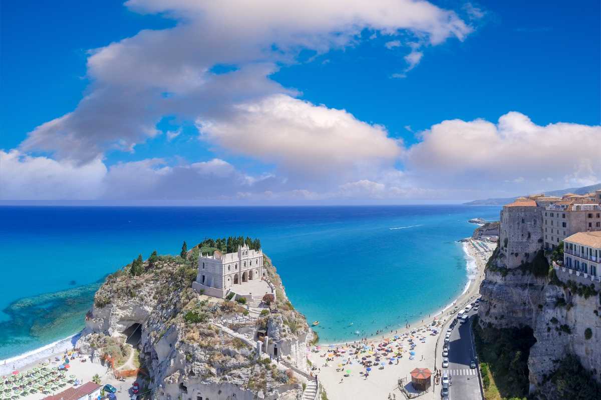 Vista panoramica di Tropea con il mare e il Santuario di Santa Maria dell'Isola, evidenziando le tradizioni locali.