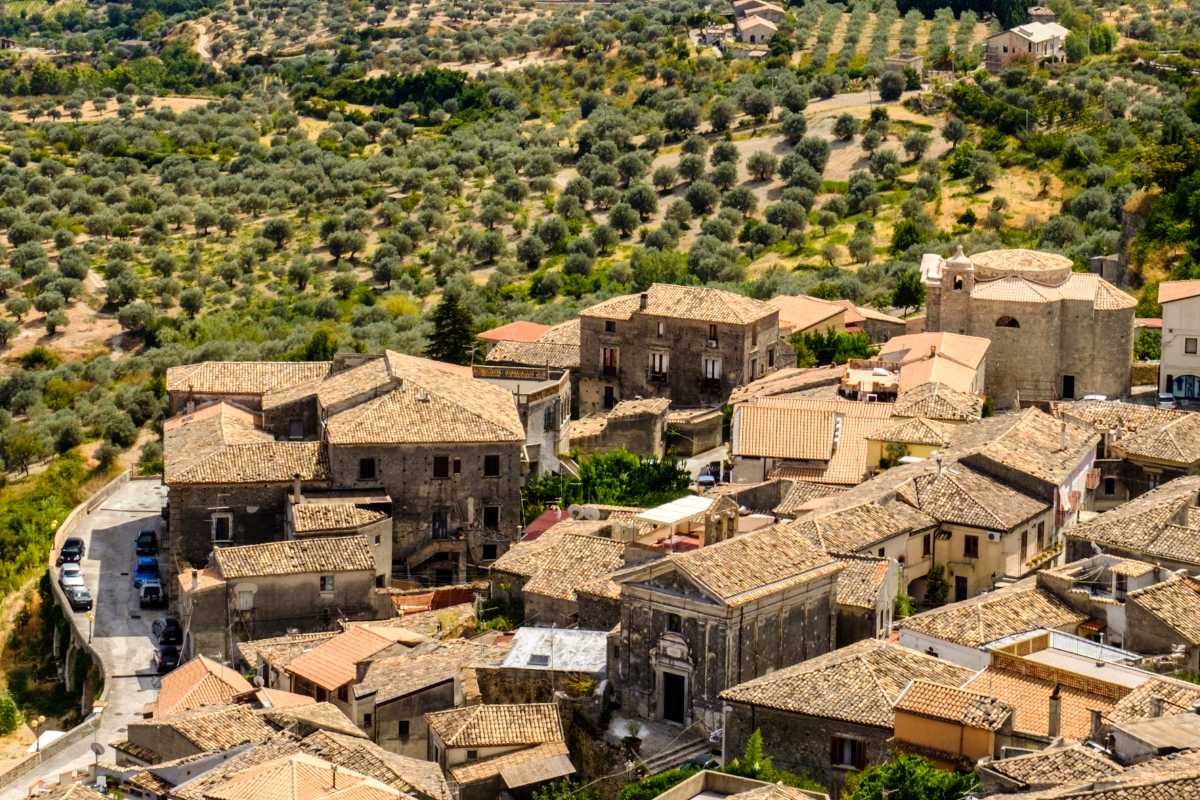 Vista panoramica del borgo di Gerace con i bambini che esplorano, includi dettagli architettonici e paesaggistici.